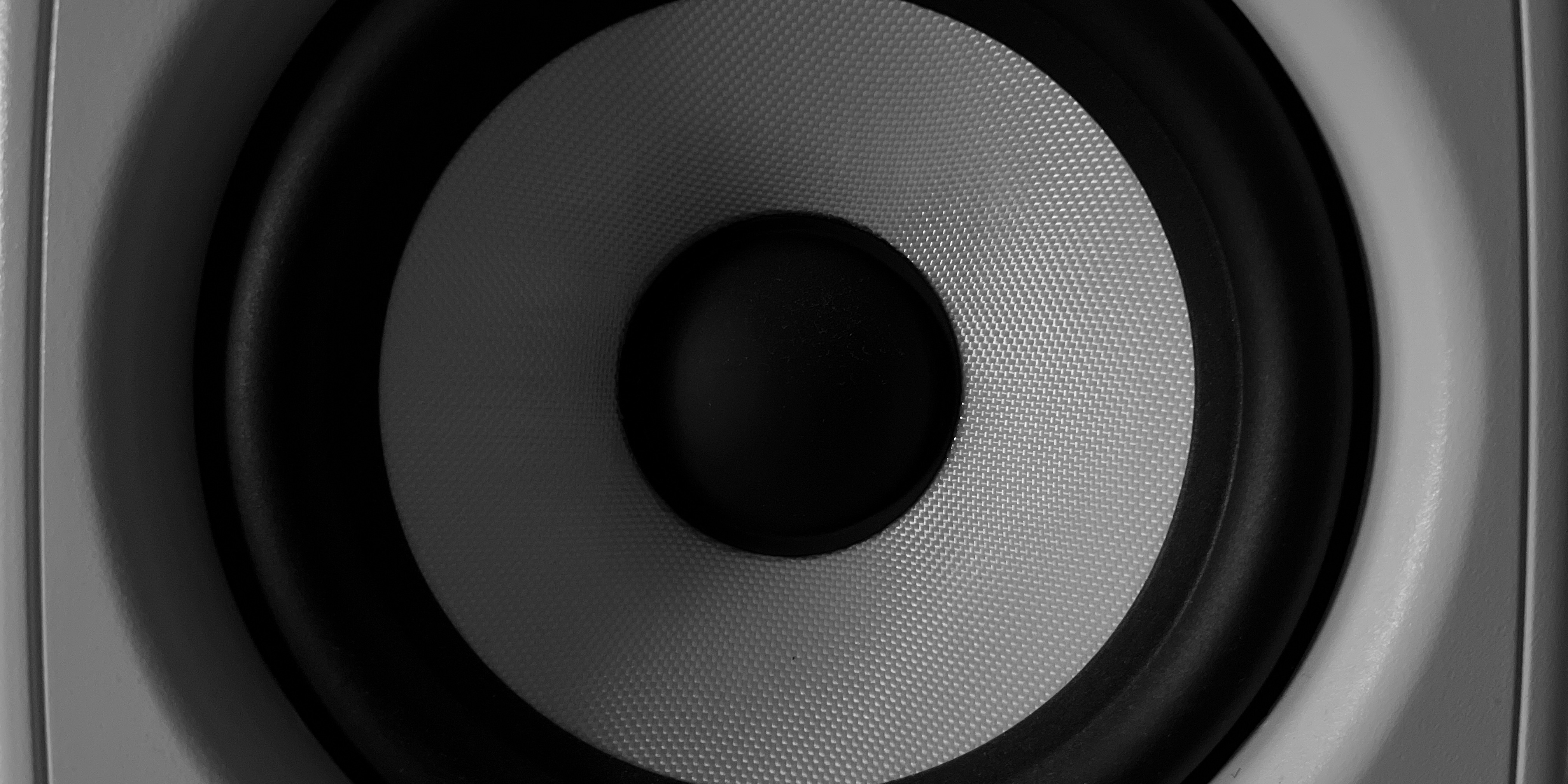 Close-up photograph of a white KRK studio monitor speaker in black and white