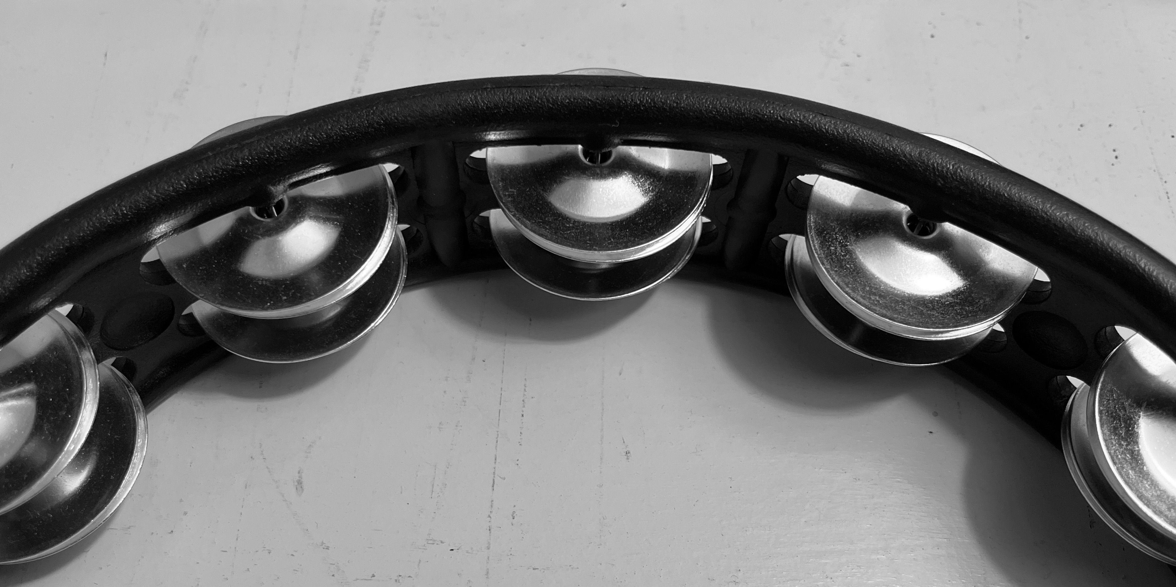 Close up image of a black plastic tambourine in black and white