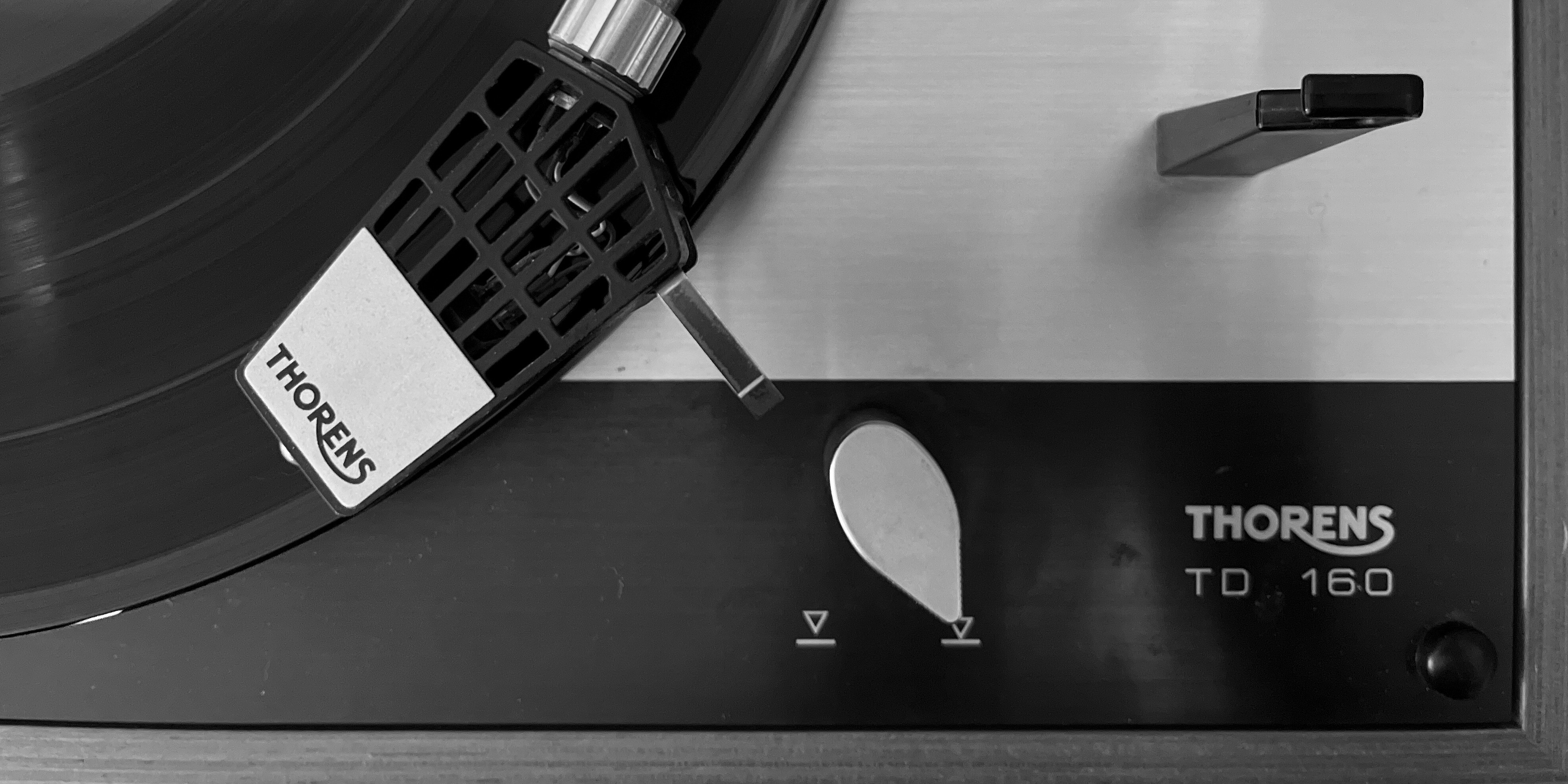 Black and white close up image of the needle on a spinning record playing on a Thorens turntable