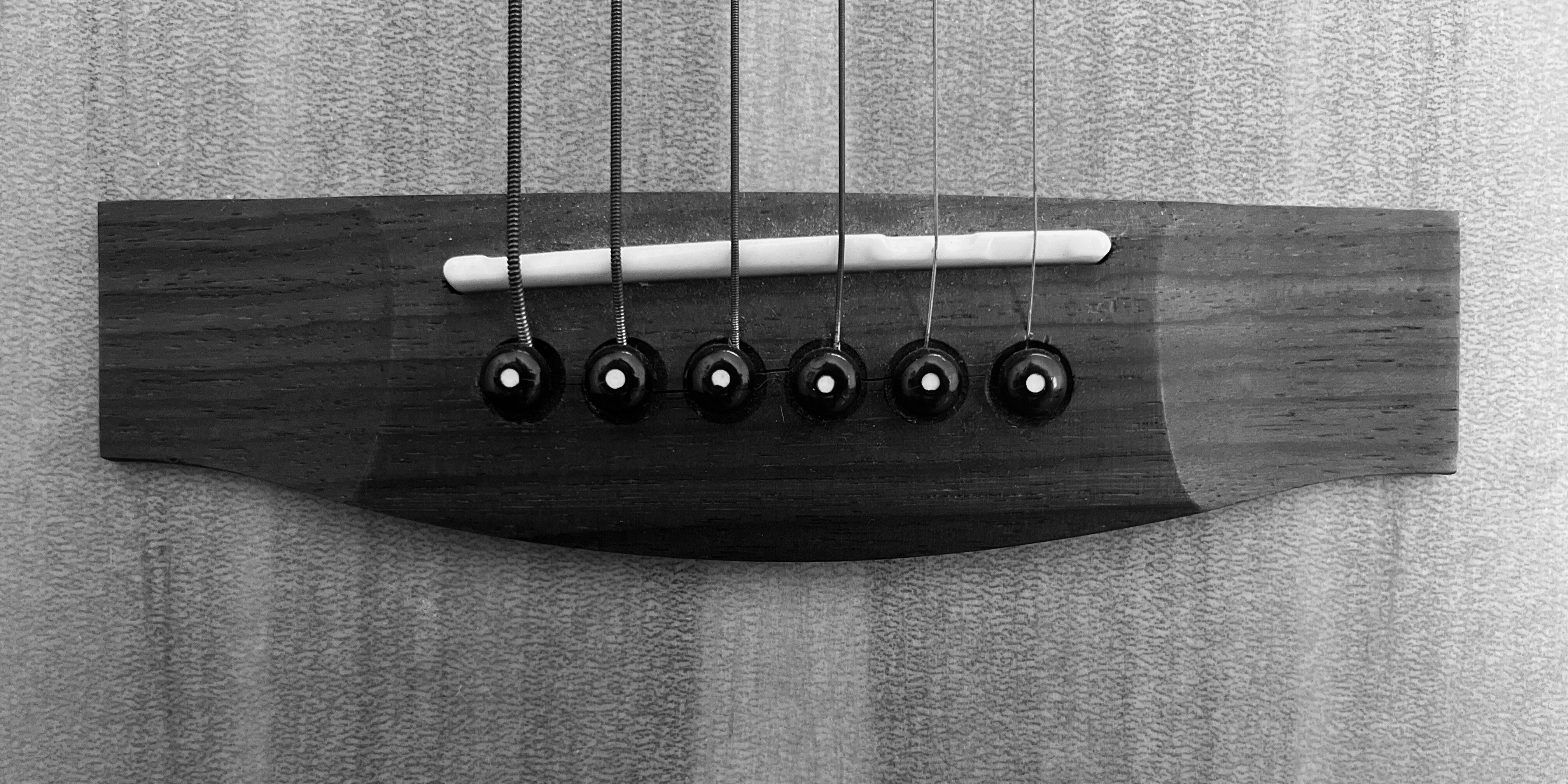 Close-up black and white image of the bridge of an acoustic guitar