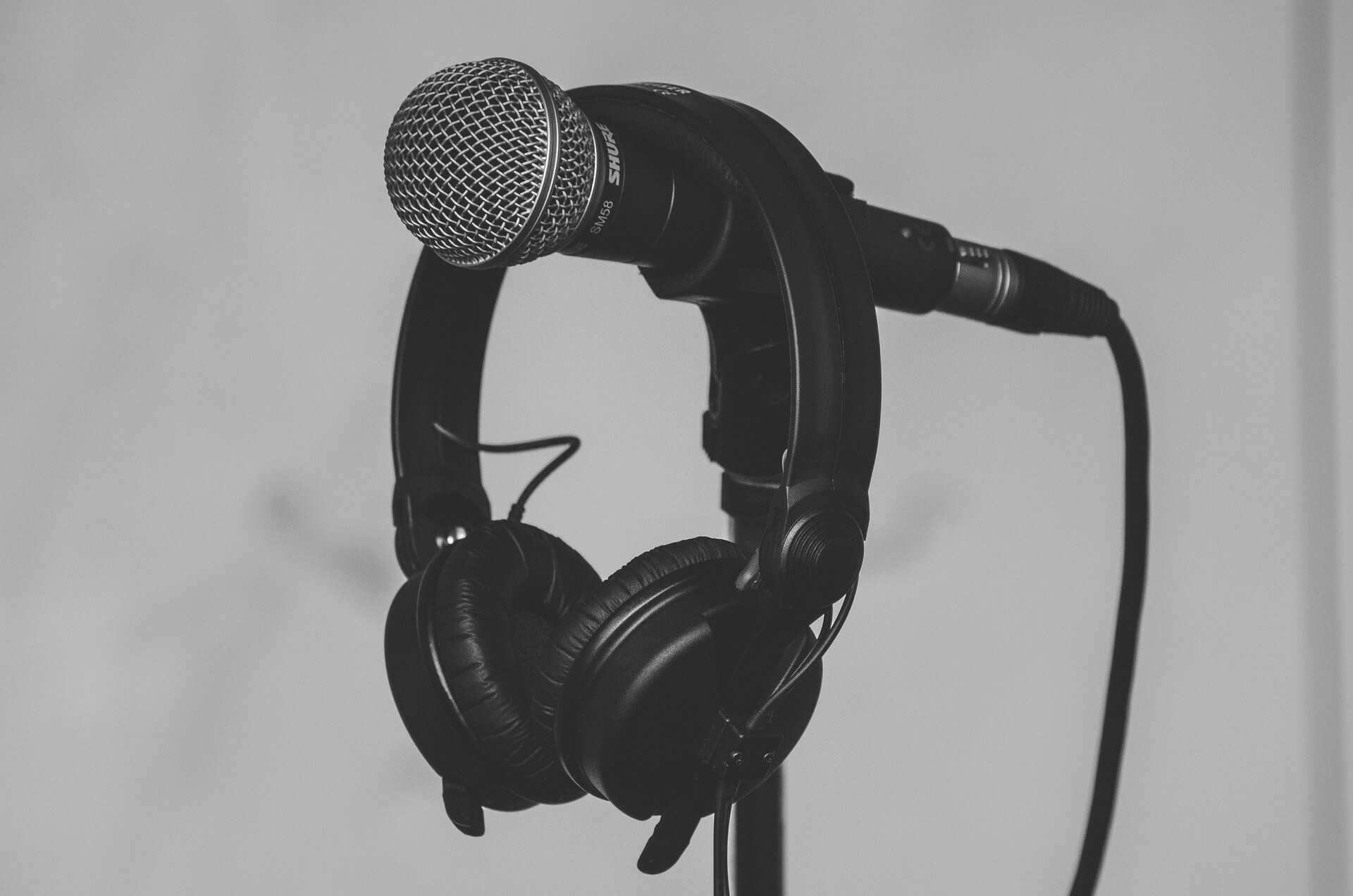 Image by Pexels from Pixabay picturing a microphone on a stand with a pair of headphones resting on top of the microphone