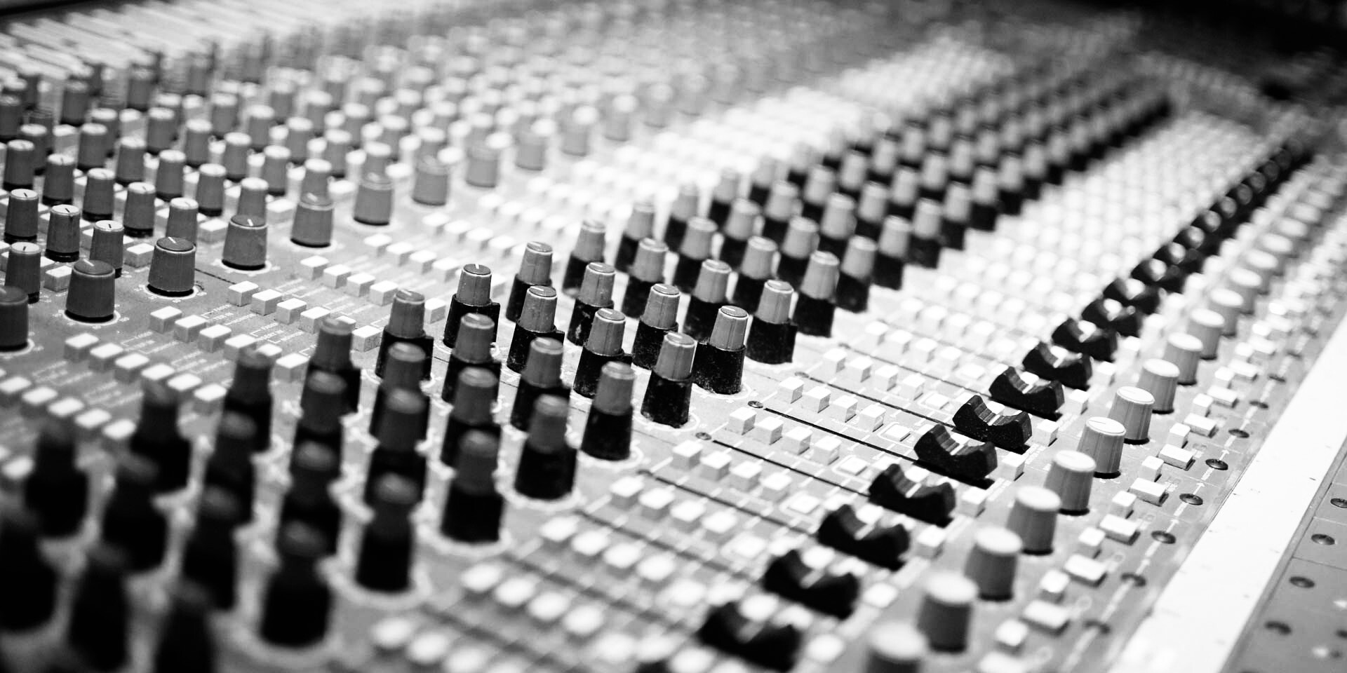 Black and white close-up image of a mixing board in a recording studio by Rieke from Pixabay