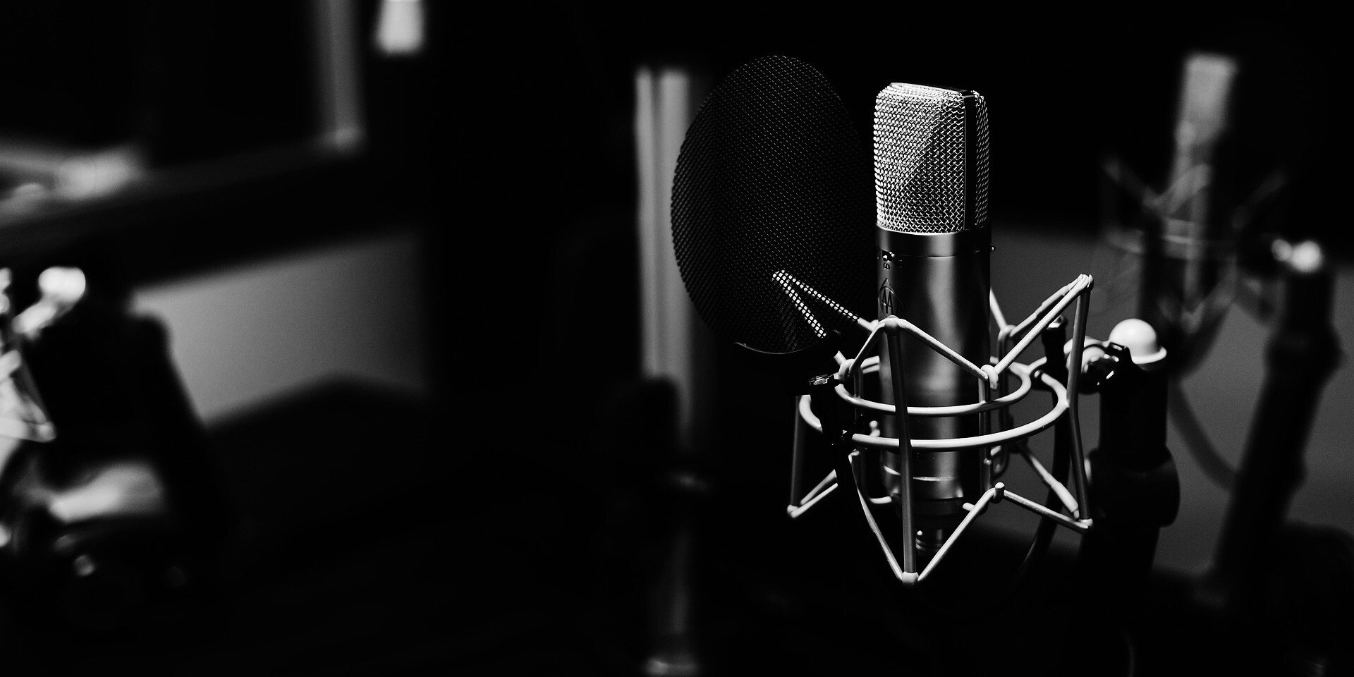 Image of a microphone in the foreground with a recording studio in the background in black and white by Pexels from Pixabay